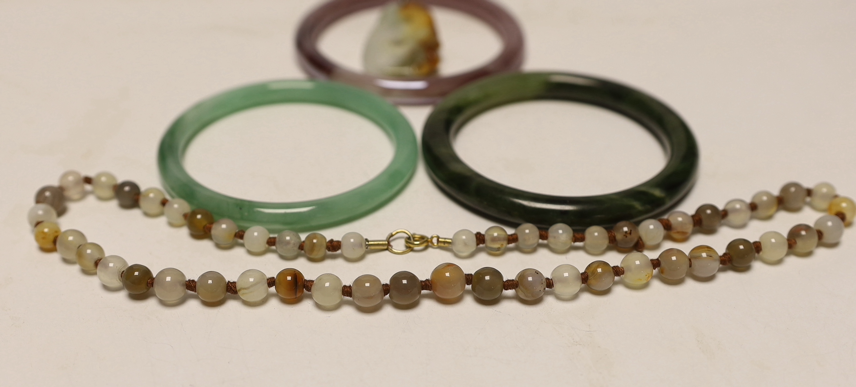 Two Chinese jade bangles, another, a jade pendant and beads